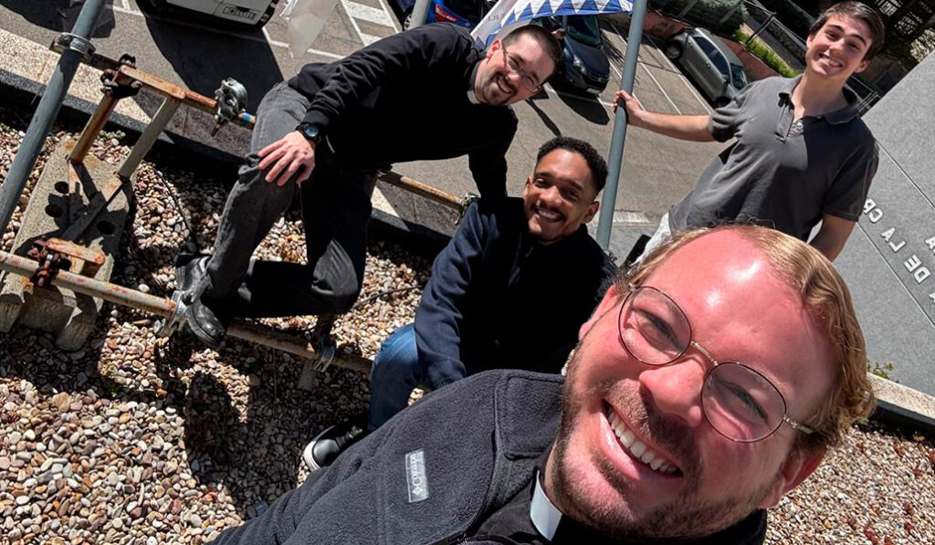 Sacerdotes y fieles de Santa Teresa Benedicta de la Cruz ponen una bandera vaticana en su fachada.