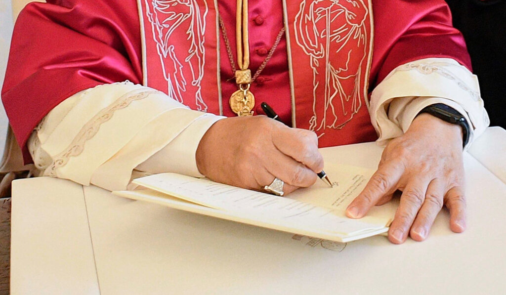 El Pontífice firma un documento en una imagen de archivo. Foto: CNS. 