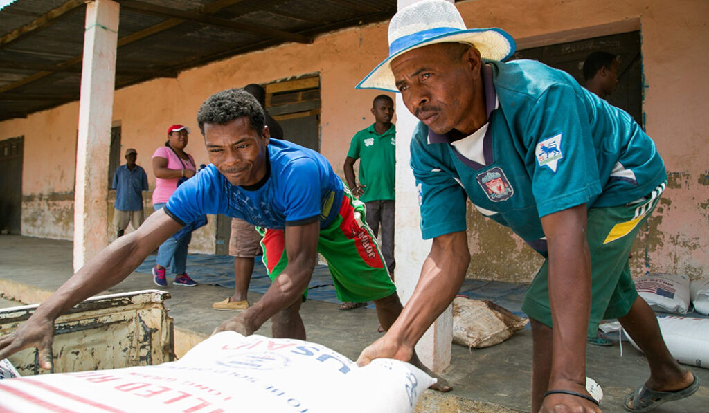 Hombres en Madagascar descargan ayuda humanitaria de Cáritas y USAID.