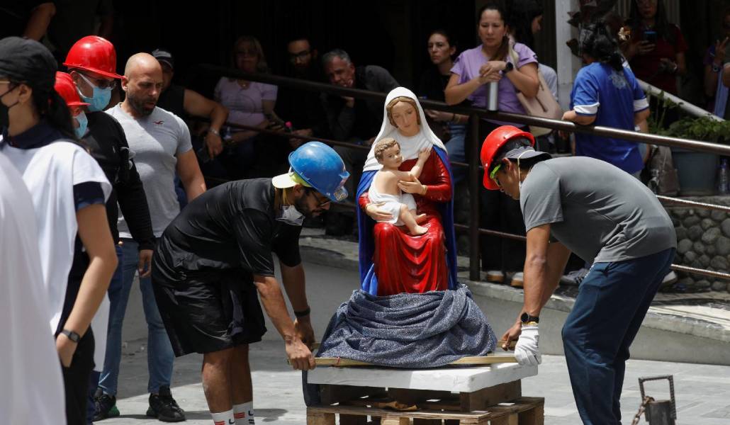 Voluntarios colocan en la calle la imagen de una Virgen y el Niño rescatada de un edificio. Foto: CNS.