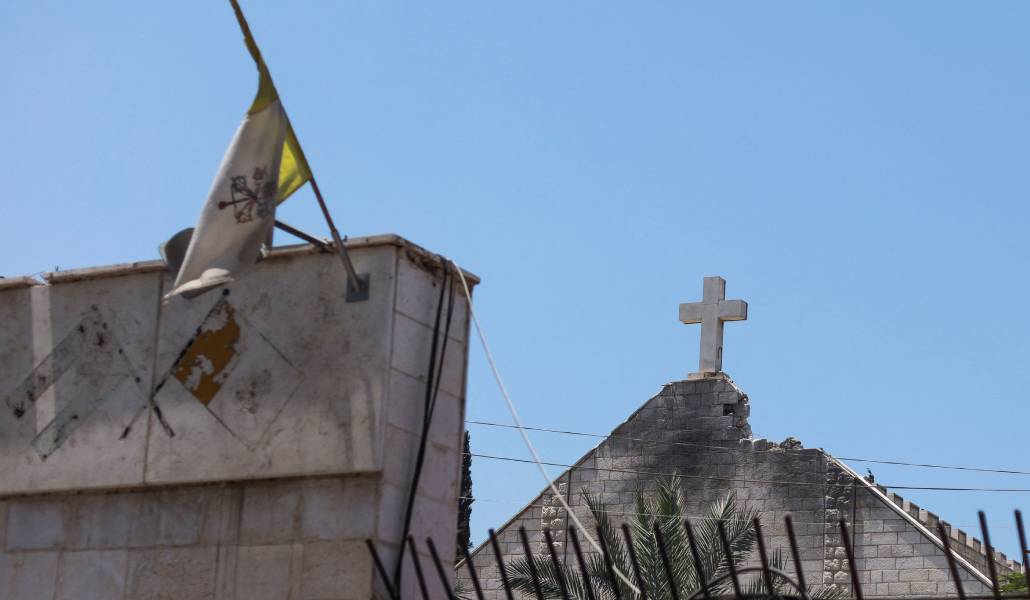 La fachada afectada por el ataque, con la bandera del Vaticano a media asta. Foto: OSV News / Reuters / Khamis al Rifi.