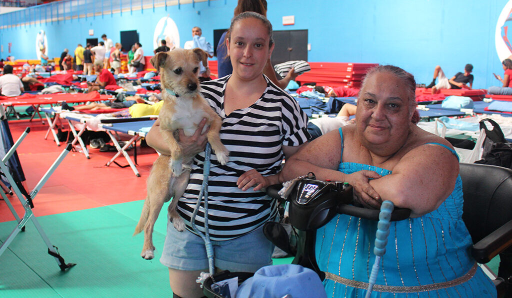 Laura recibe ayuda para acostarse y levantase. A la izquierda, su hija Irene con su perro.