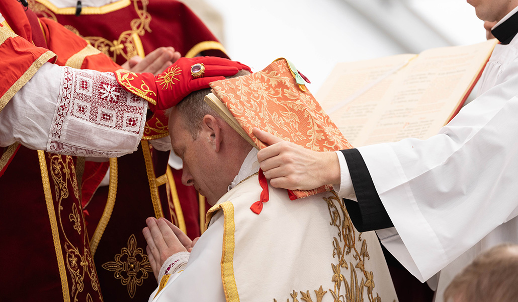 El padre estadounidense Michael Goldade se inclina con los Evangelios sobre sus hombros mientras el obispo Alfonso de Galarreta le impone las manos durante una ordenación episcopal sin aprobación papal para la Fraternidad de San Pío X en Ecône, Suiza, el 1 de julio de 2026.